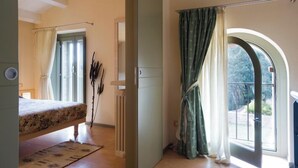 Una stanza con un letto, un termosifone, una finestra con tende e vista sull'esterno.