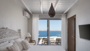 Quarto com uma cama grande, TV e vista para o mar.