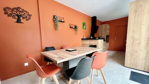 Zona pranzo moderna con tavolo e sedie in legno, una cucina sullo sfondo e un ampio guardaroba.
