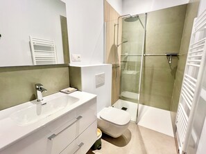 A modern bathroom with a white sink, a toilet, and a glass-enclosed shower. - Large house 10 minutes from the town centre - Nice garden and petanque area (La Rochelle)