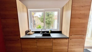 Cucina compatta con finestra, mobili in legno e piano di lavoro nero.