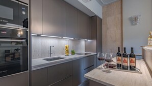 Une cuisine moderne équipée d’un four Bosch, d’appareils électroménagers en acier inoxydable, d’un plan de travail en marbre et d’un espace dédié à la dégustation de vins.