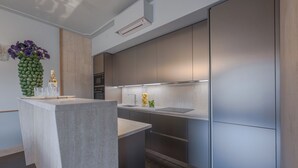 Une cuisine moderne dotée d’un îlot central, d’appareils électroménagers en acier inoxydable et d’un revêtement mural en bois clair.