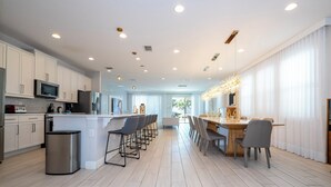 A modern kitchen with white cabinets, stainless steel appliances, and a central island with bar stools.