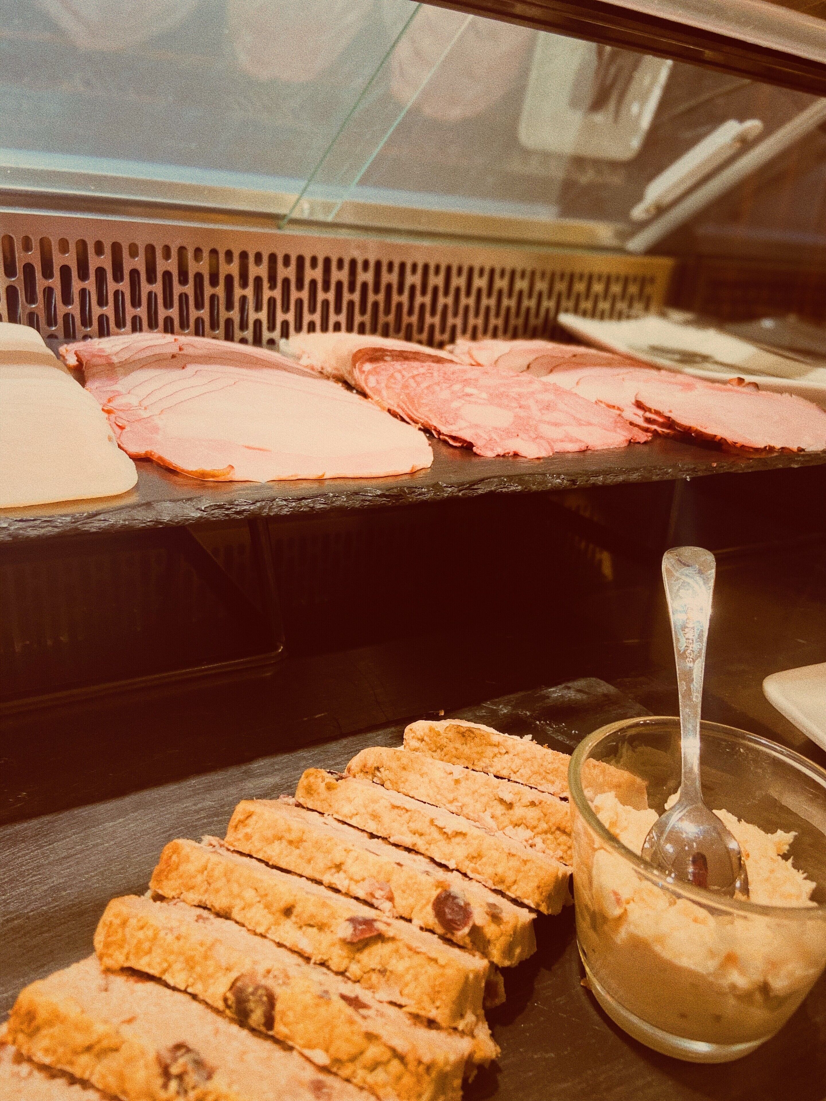 A display case with various food items, including sliced meats and pastries.