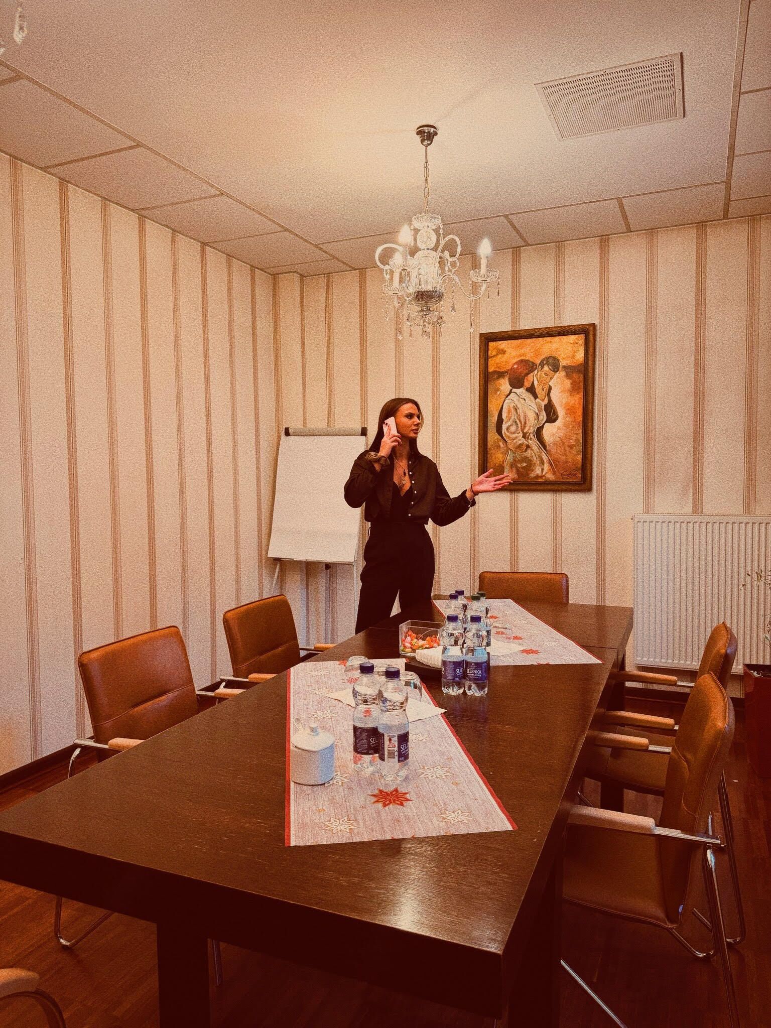 A conference room with a long table, chairs, water bottles, and a painting on the wall.