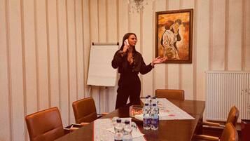 A conference room with a long table, chairs, water bottles, and a painting on the wall.