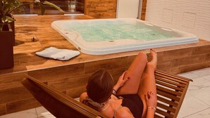 A person relaxing on a wooden bench in a spa area with a hot tub. - Hotel Borowiecki (Lódz)