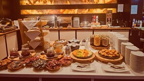 A buffet setup with various food items, a coffee station, and a seating area with a chair and table. - Hotel Borowiecki (Lódz)