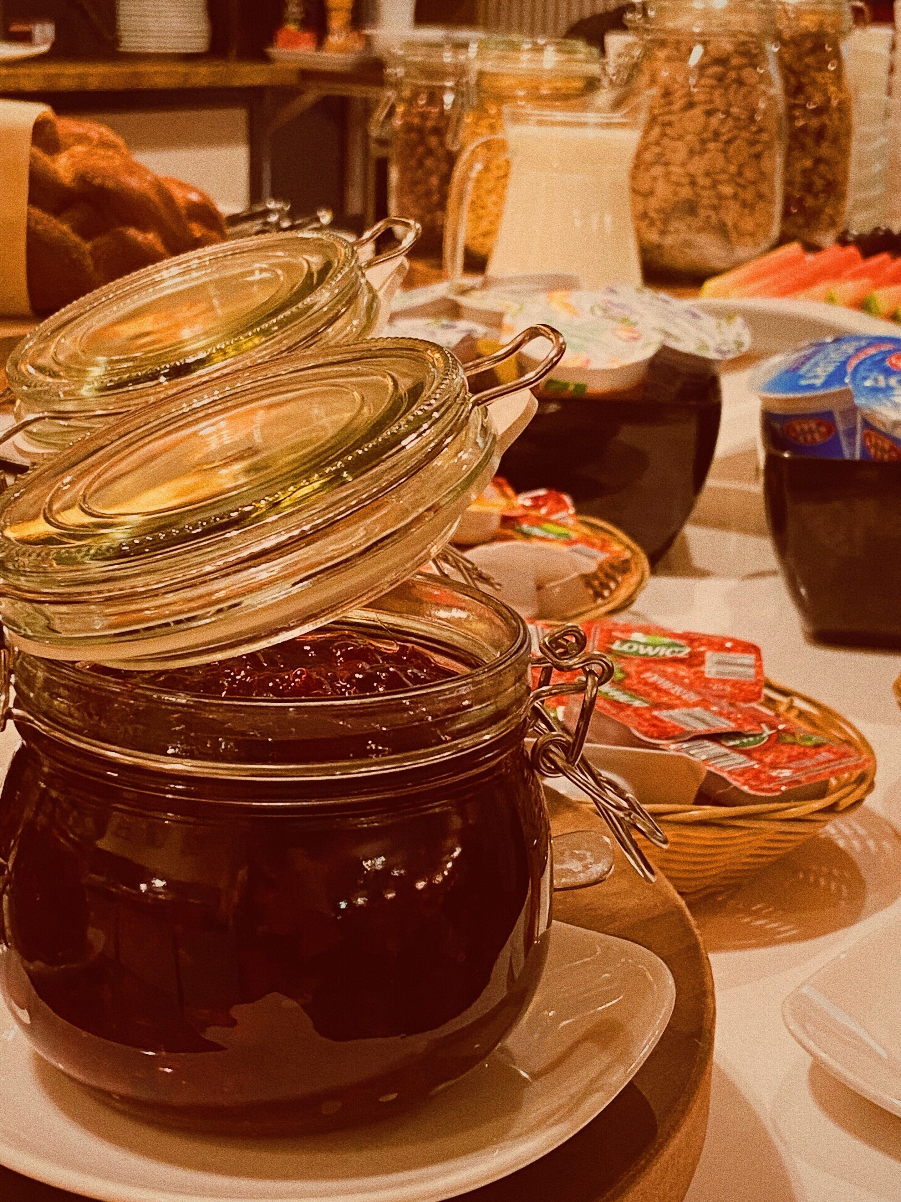 A breakfast buffet with various food items and condiments, including a jar of jam and a pitcher of milk.