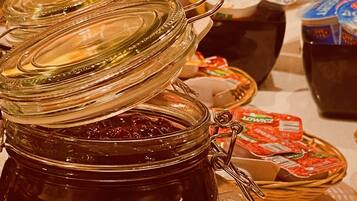 A breakfast buffet with various food items and condiments, including a jar of jam and a pitcher of milk.