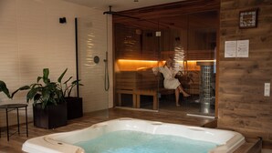 A spa area with a hot tub, wooden flooring, and a glass door leading to a sauna room. - Hotel Borowiecki (Lódz)