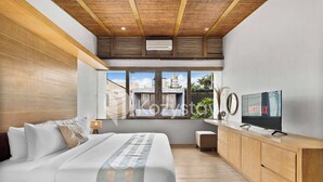 A modern bedroom with a large bed, a wooden headboard, a TV on a wooden console, and a window with a city view.
