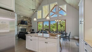 Una cocina amplia con una isla grande, vigas de techo de madera y una chimenea de piedra.