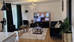 A modern living room with a TV, black furniture, a coffee table, and a plant. - 5 Guests - Pet Friendly - Balcony & Free Parking (Dartford)