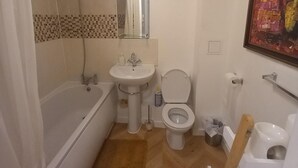 A bathroom with a bathtub, sink, toilet, and a shower curtain. - 5 Guests - Pet Friendly - Balcony & Free Parking (Dartford)