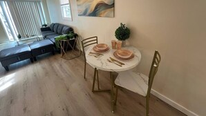 Un comedor con una mesa redonda, sillas doradas y piso de mármol.