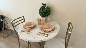 Una mesa redonda con cuatro sillas, una pequeña planta en maceta y un florero con flores.