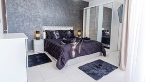 A modern bedroom with a large bed, bedside tables, a wardrobe, and a TV. - D Pool Top (L-Imsida)