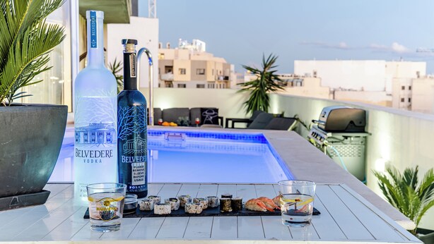 A rooftop bar with a pool, Belvedere vodka bottle, glasses, and sushi. - D Pool Top (L-Imsida)
