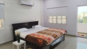 Une chambre à coucher comprenant un lit, un ventilateur de plafond, un appareil de climatisation, une fenêtre avec des stores et une vue sur l’extérieur.