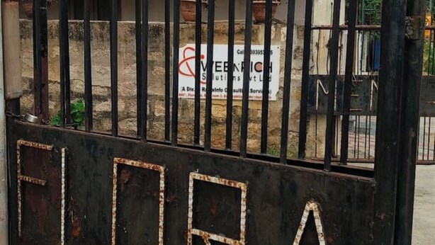 Une grille en métal sur laquelle on peut lire le mot « FLORA », avec une enseigne en arrière-plan.