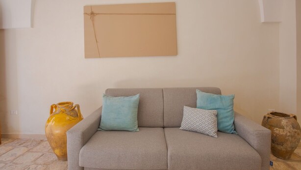 A living room with a grey sofa, two light blue pillows, a patterned pillow, and a yellow vase.