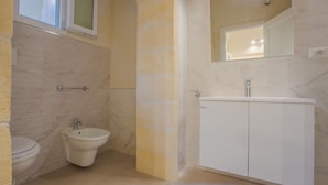 A bathroom with a toilet, bidet, and a sink with a mirror above it.