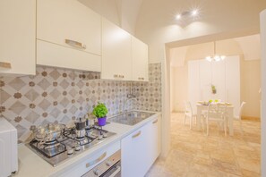 A modern kitchen with white cabinets, a gas stove, and a dining area with a table and chairs.