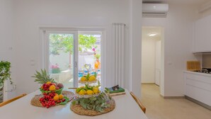 Una cucina moderna con mobili bianchi e un'area pranzo con tavolo bianco apparecchiato con frutta e un libro.