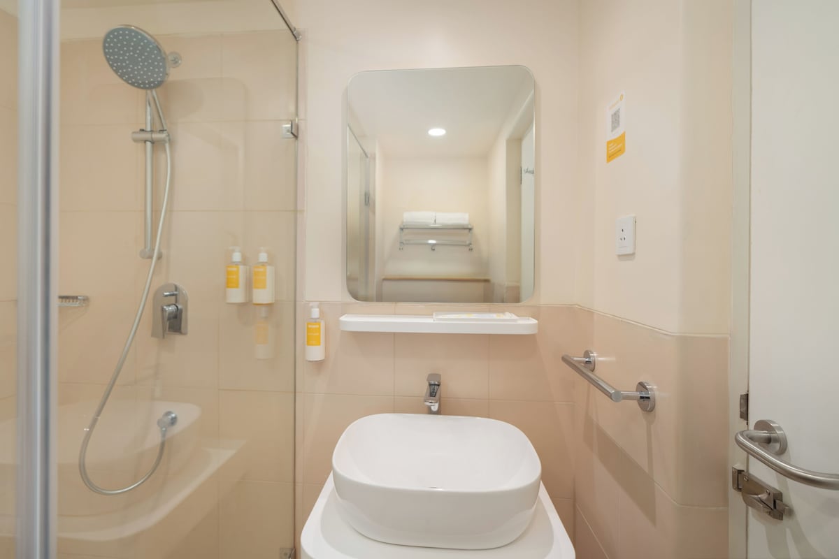 A modern bathroom with a shower, toilet, and a mirror above the sink.