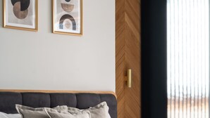 A neatly made bed with a wooden headboard, grey pillows, and a book on the bed. Two framed abstract artworks are hung on the wall above the bed. - Tarasowa Polana (Koscielisko)