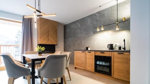 A modern kitchen with wooden cabinets, a dining table with chairs, and pendant lighting. - Tarasowa Polana (Koscielisko)