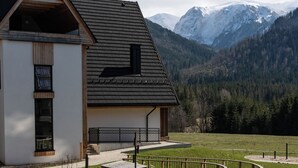 A building with a sloped roof, a playground with a seesaw and swings, and a view of snow-capped mountains. - Tarasowa Polana (Koscielisko)