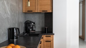 A modern kitchen with a black countertop, wooden cabinets, a coffee machine, and a pendant light. - Tarasowa Polana (Koscielisko)