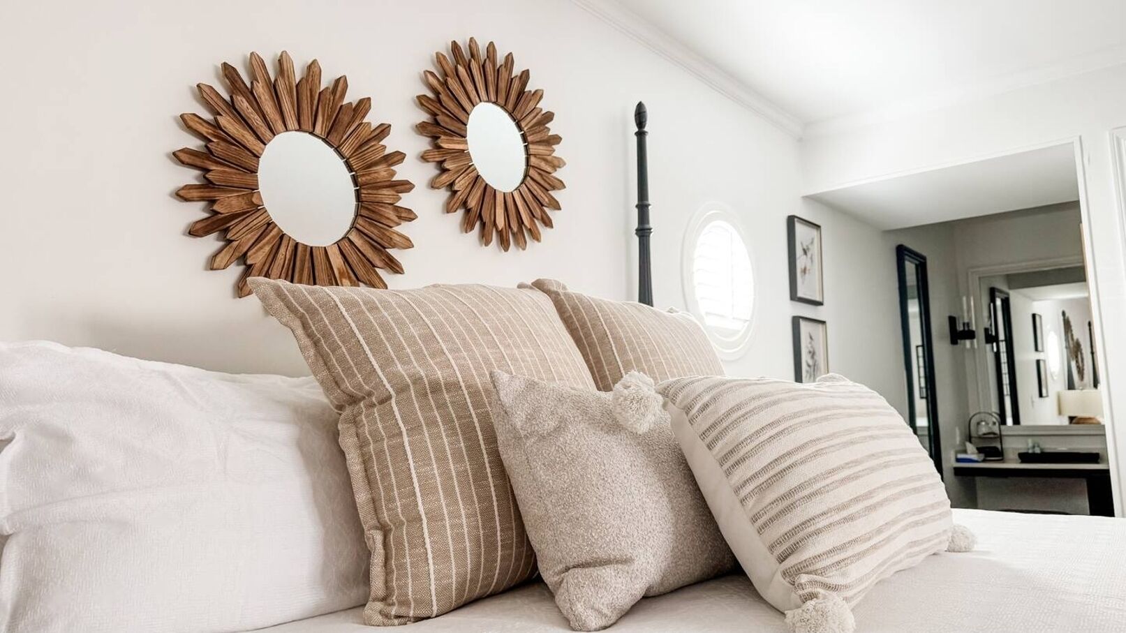 Une chambre à coucher avec un lit, deux miroirs en forme de soleil et une table de chevet avec une lampe.