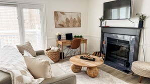 A cozy living room with a sofa, coffee table, fireplace, and a television.