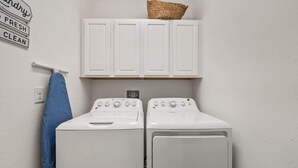 A laundry area with two white washing machines and a white cabinet above them. - 8848 Cabot Cliffs Drive (Davenport)