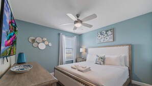 A bedroom with a bed, a ceiling fan, a TV, and a decorative wall. - 8848 Cabot Cliffs Drive (Davenport)
