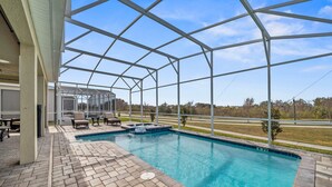 A covered outdoor swimming pool with a brick patio, lounge chairs, and a hot tub. - 8848 Cabot Cliffs Drive (Davenport)