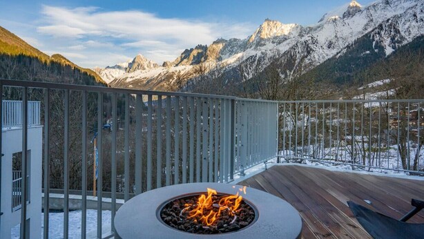 A deck with a fire pit overlooking a mountainous landscape.