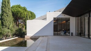 A modern building with a courtyard, a reflective water feature, and a glass facade. -  Limehome Lisbon Campo Pequeno (Lisbon)