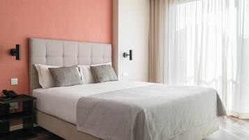 A hotel room with a bed, a nightstand, a telephone, and a window with curtains.