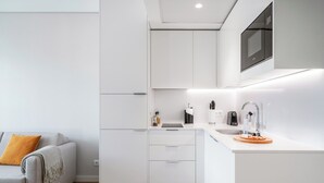 A modern kitchen with white cabinetry, a built-in microwave, a coffee maker, and a sink. -  Limehome Lisbon Campo Pequeno (Lisbon)