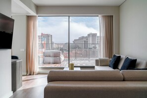 A modern living room with a large window, a sofa, a TV, and a balcony with a view of the city. -  Limehome Lisbon Campo Pequeno (Lisbon)