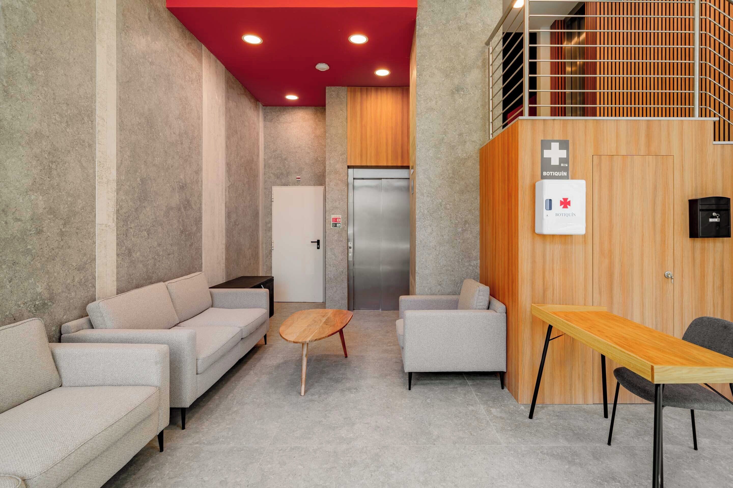 A modern waiting area with sofas, a wooden table, and a reception desk.