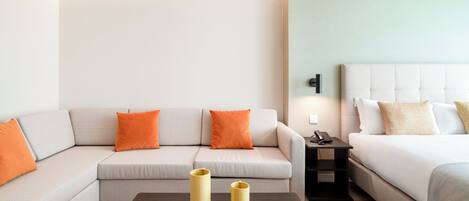 Una habitación de hotel moderna con sofá, cama y una mesita con dos jarrones.