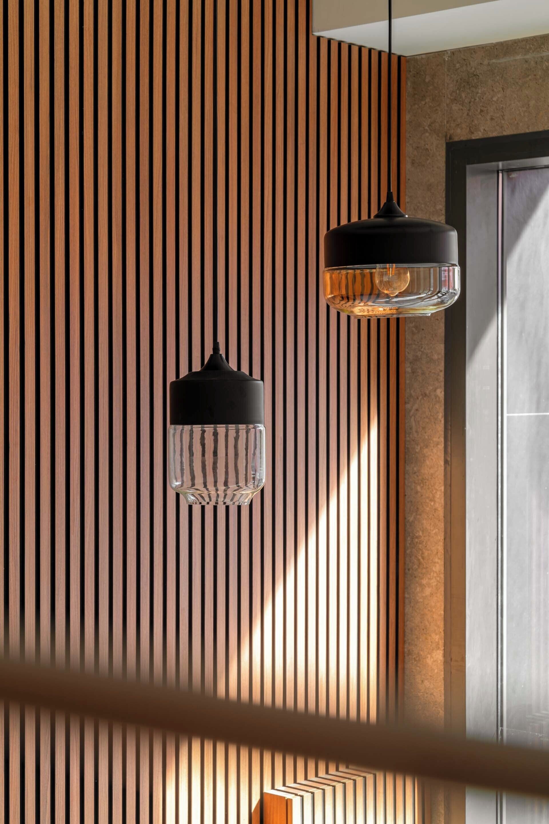 A modern interior with vertical wooden slats and two pendant lights.