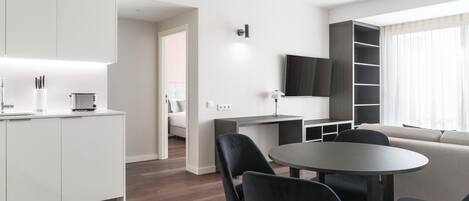 A modern living space with a kitchen, dining area, and a seating area with a TV.