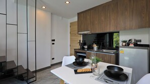 A modern kitchen with a white table, black cookware, and a glass vase.